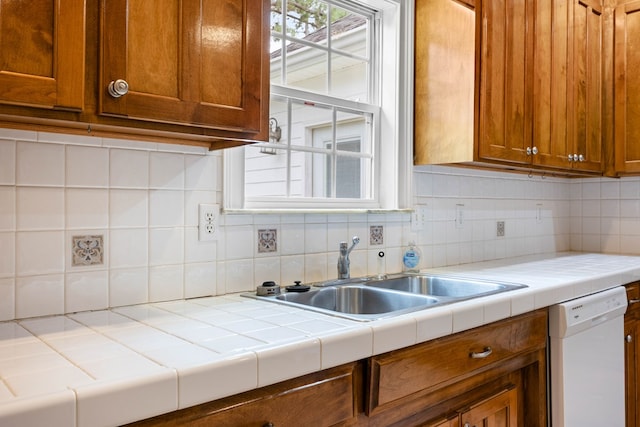 4143 Whithorn Way, Valdosta, GA 31605 - kitchen with white dishwasher, brown cabinets, tasteful backsplash, a sink, and tile countertops