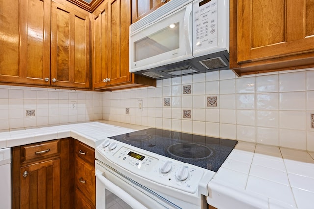 4143 Whithorn Way, Valdosta, GA 31605 - kitchen featuring white appliances, tile countertops, brown cabinetry, and tasteful backsplash