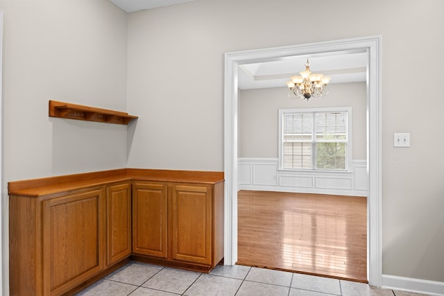 4143 Whithorn Way, Valdosta, GA 31605 - interior space with a chandelier, light tile patterned floors, brown cabinets, a tray ceiling, and a wainscoted wall