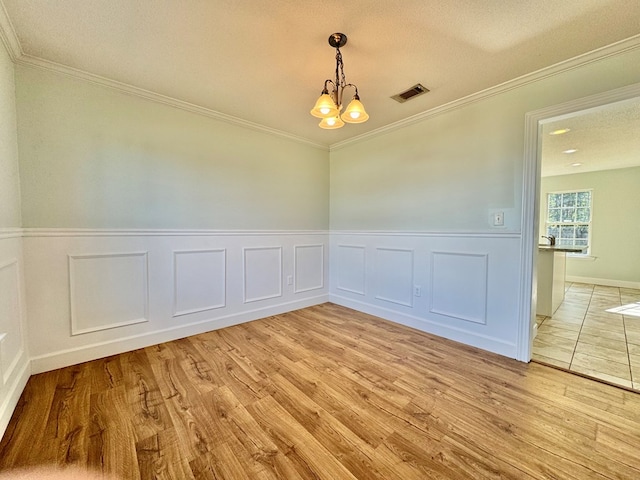 unfurnished room with a chandelier, a textured ceiling, light hardwood / wood-style flooring, and crown molding