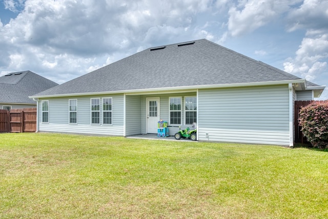 back of property with a yard, fence, and roof with shingles