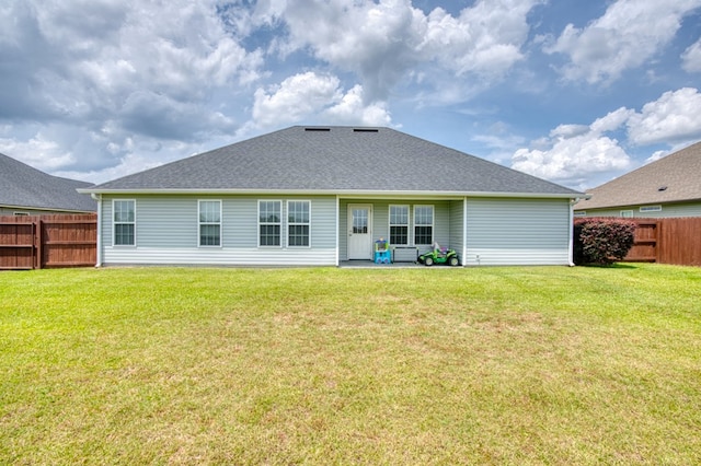 back of property with a lawn, fence, and roof with shingles