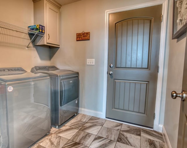 laundry room featuring washing machine and dryer, baseboards, and cabinet space