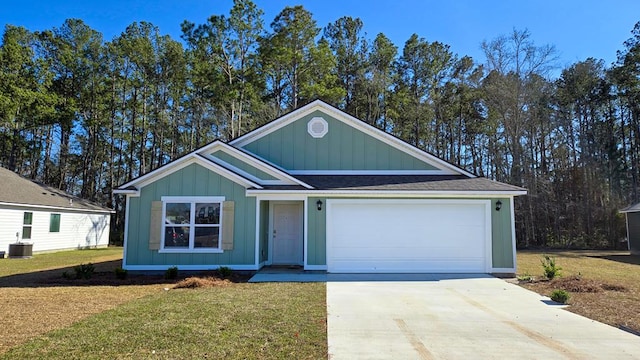 view of front of property featuring an attached garage, central AC, concrete driveway, board and batten siding, and a front yard