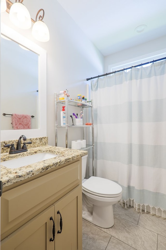 bathroom featuring tile patterned flooring, vanity, toilet, and walk in shower