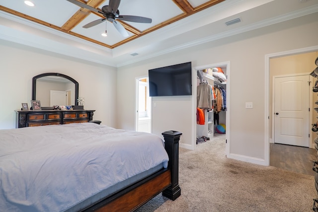 bedroom with a spacious closet, ceiling fan, coffered ceiling, crown molding, and a closet