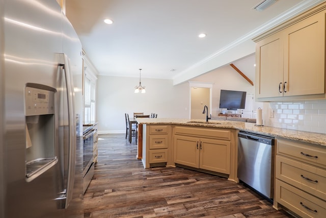 kitchen featuring pendant lighting, dark wood-type flooring, cream cabinets, sink, and appliances with stainless steel finishes