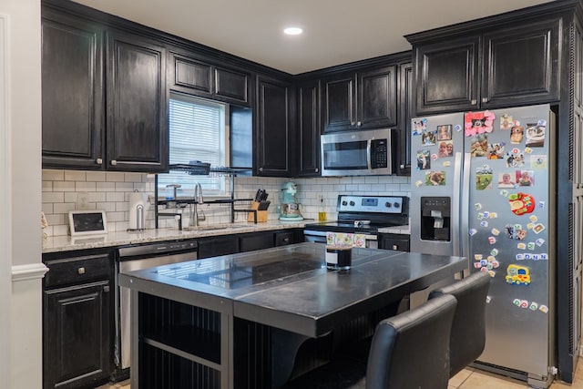 5187 Calvary Cir, Valdosta, GA 31605 - kitchen with stainless steel appliances, dark cabinetry, a breakfast bar area, and decorative backsplash