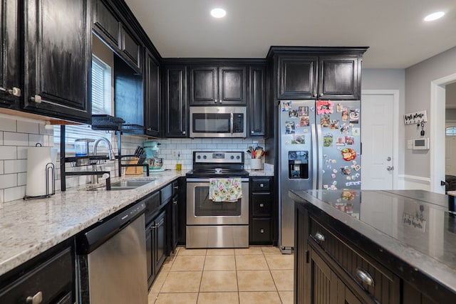 5187 Calvary Cir, Valdosta, GA 31605 - kitchen with appliances with stainless steel finishes, dark cabinets, tasteful backsplash, light stone counters, and light tile patterned floors