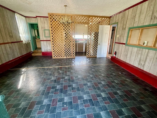 empty room featuring a textured ceiling, wooden walls, and ornamental molding