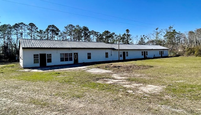 back of house featuring a lawn and metal roof