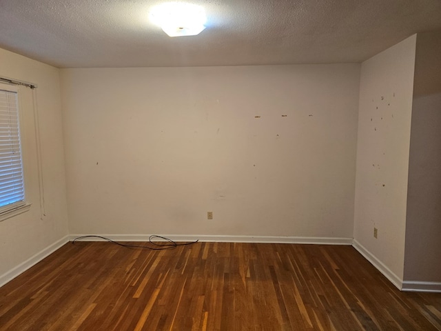 spare room featuring dark hardwood / wood-style floors and a textured ceiling