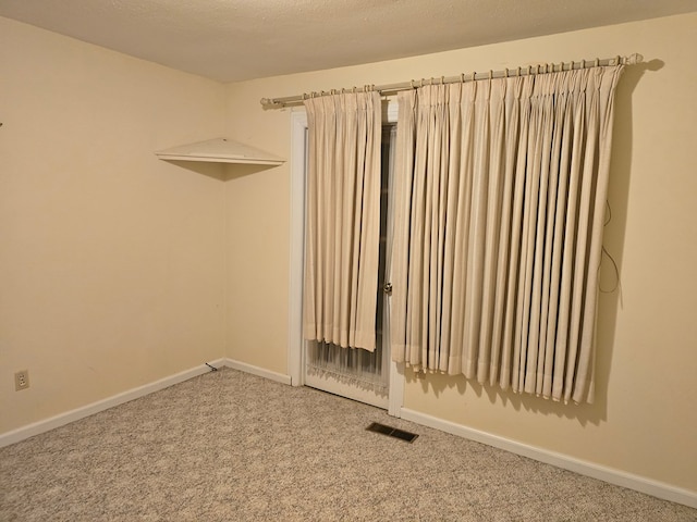 unfurnished room with carpet and a textured ceiling