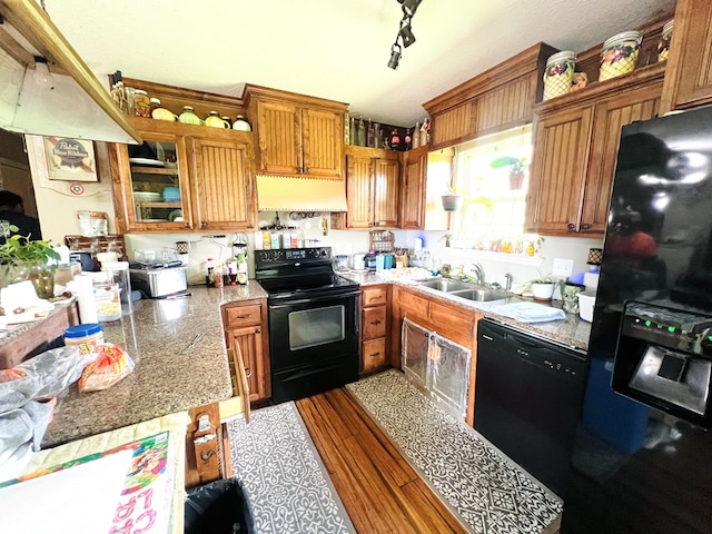 5612 Emily Ln, Hahira, GA 31632 - kitchen with black appliances, range hood, a peninsula, brown cabinetry, and wood finished floors