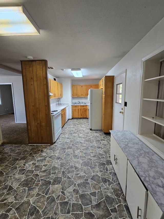 kitchen featuring light countertops, stone floors, brown cabinetry, and white appliances