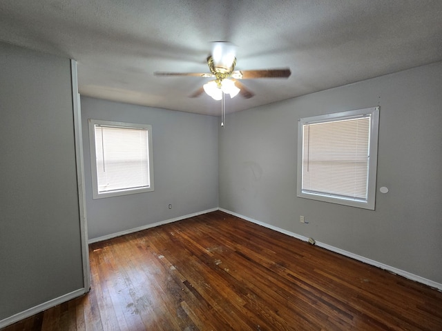 unfurnished room with ceiling fan, baseboards, and dark wood-type flooring