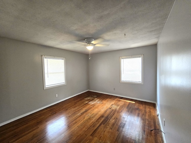 spare room featuring a ceiling fan, a wealth of natural light, wood-type flooring, and a textured ceiling