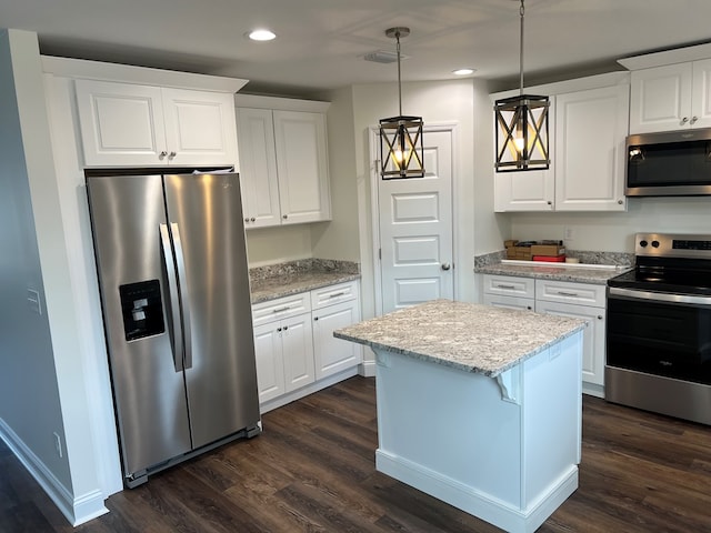 kitchen featuring light stone countertops, white cabinetry, a center island, hanging light fixtures, and appliances with stainless steel finishes