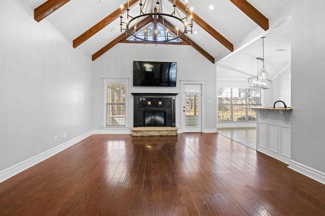 unfurnished living room featuring high vaulted ceiling, a fireplace, hardwood / wood-style floors, and an inviting chandelier