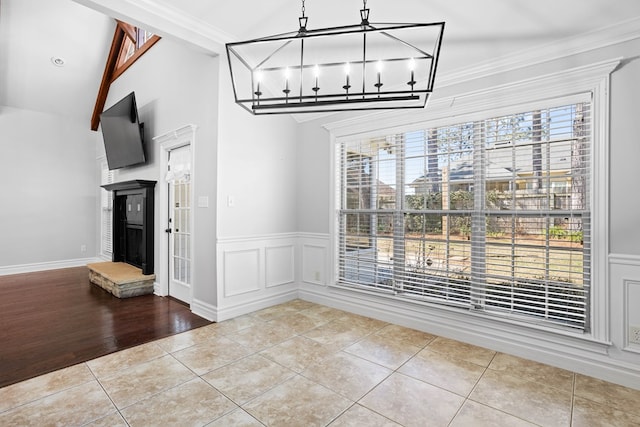 unfurnished dining area featuring tile patterned flooring, a wainscoted wall, a decorative wall, and an inviting chandelier