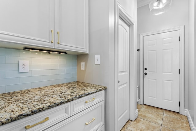 kitchen with light tile patterned floors, decorative backsplash, white cabinetry, and light stone countertops