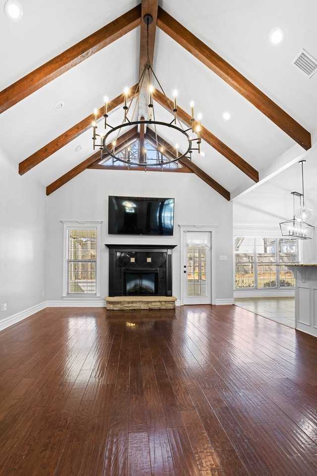 unfurnished living room featuring a glass covered fireplace, visible vents, a notable chandelier, and hardwood / wood-style flooring