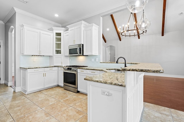 kitchen with a peninsula, appliances with stainless steel finishes, arched walkways, and light tile patterned flooring