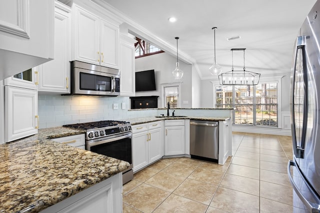 kitchen with a peninsula, vaulted ceiling, stainless steel appliances, white cabinetry, and a sink