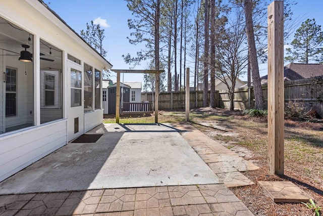 view of patio / terrace featuring an outbuilding, a fenced backyard, a storage shed, a sunroom, and a ceiling fan