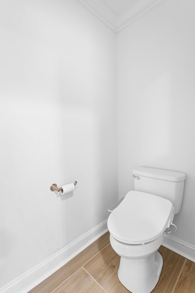 bathroom with ornamental molding, wood finished floors, toilet, and baseboards