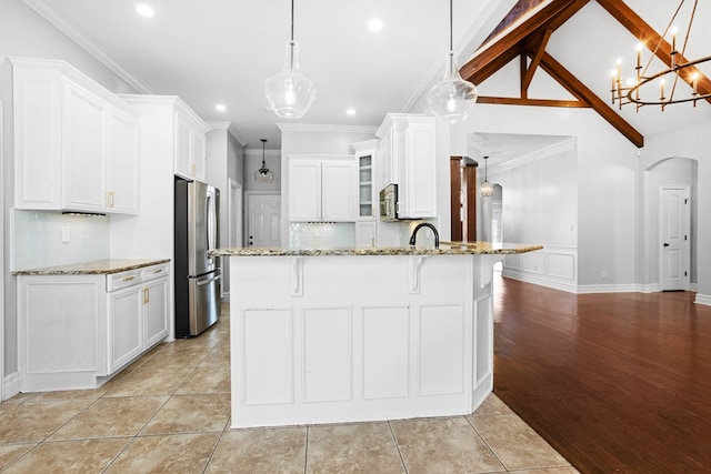 kitchen featuring arched walkways, stainless steel appliances, ornamental molding, light stone countertops, and a kitchen bar