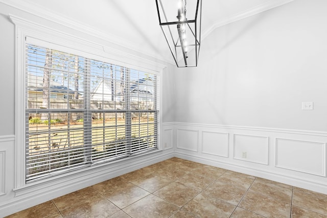 unfurnished dining area with a decorative wall, a wainscoted wall, ornamental molding, tile patterned floors, and an inviting chandelier