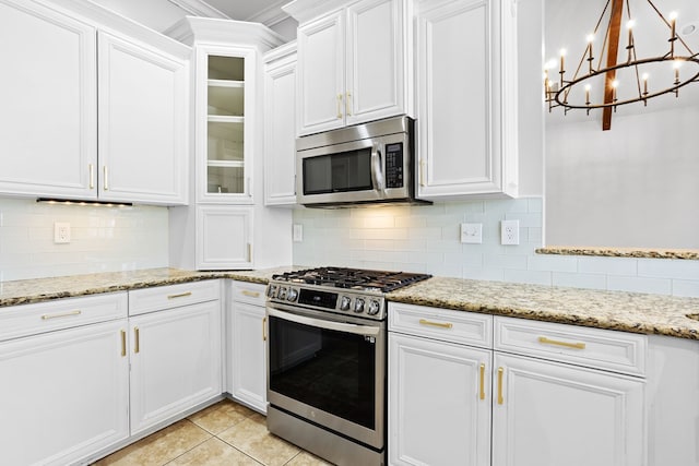 kitchen with stainless steel appliances, tasteful backsplash, white cabinetry, and light tile patterned floors