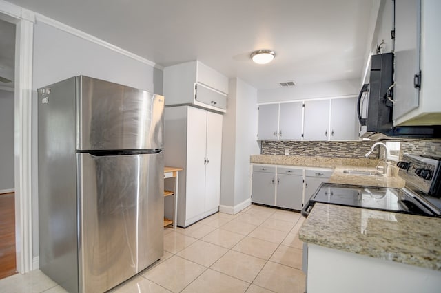 2321 Frederick Pl, Valdosta, GA 31602 - kitchen with appliances with stainless steel finishes, backsplash, light tile patterned floors, and light stone countertops