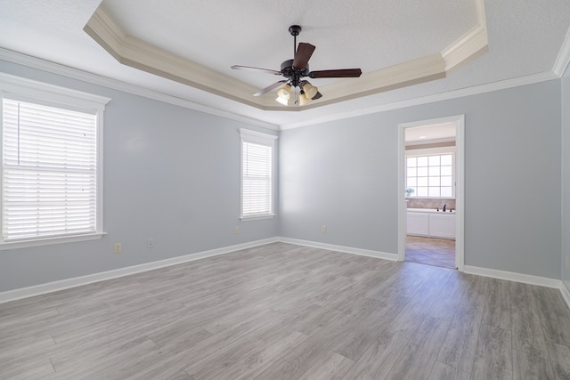 spare room featuring a textured ceiling, ornamental molding, a raised ceiling, ceiling fan, and light hardwood / wood-style floors