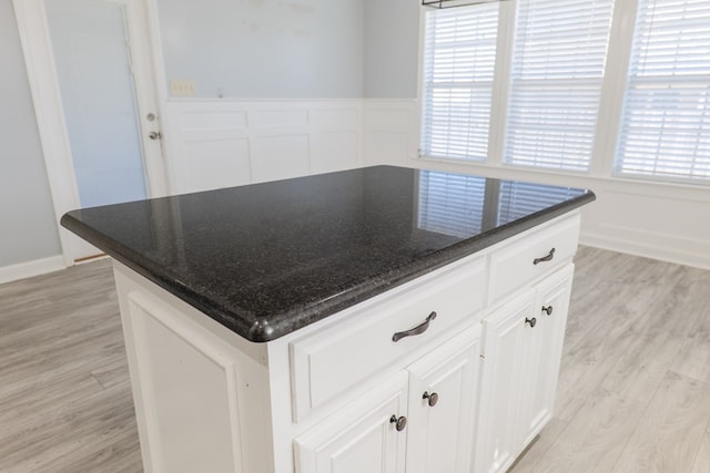 kitchen with white cabinetry, a center island, and light hardwood / wood-style flooring