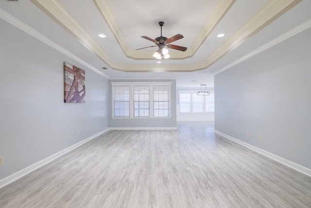 unfurnished room featuring ceiling fan with notable chandelier, ornamental molding, a tray ceiling, and light hardwood / wood-style floors