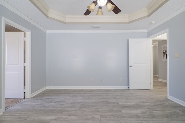 spare room featuring ornamental molding, a raised ceiling, and light hardwood / wood-style flooring