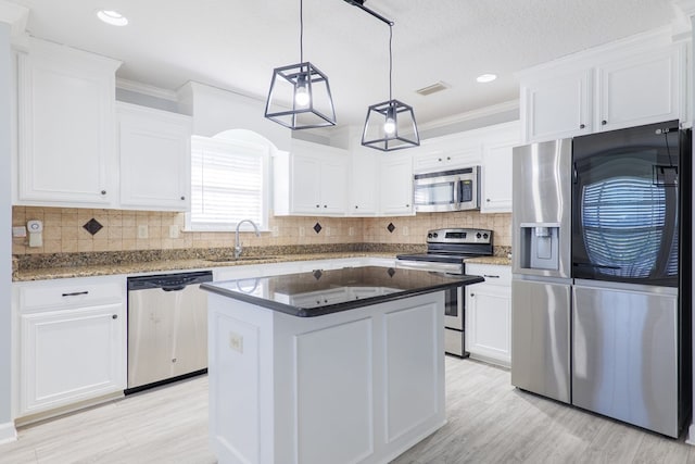 kitchen featuring sink, white cabinetry, stainless steel appliances, a kitchen island, and decorative light fixtures