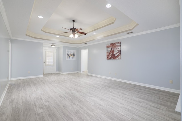 unfurnished room featuring ornamental molding, ceiling fan, light wood-type flooring, and a tray ceiling