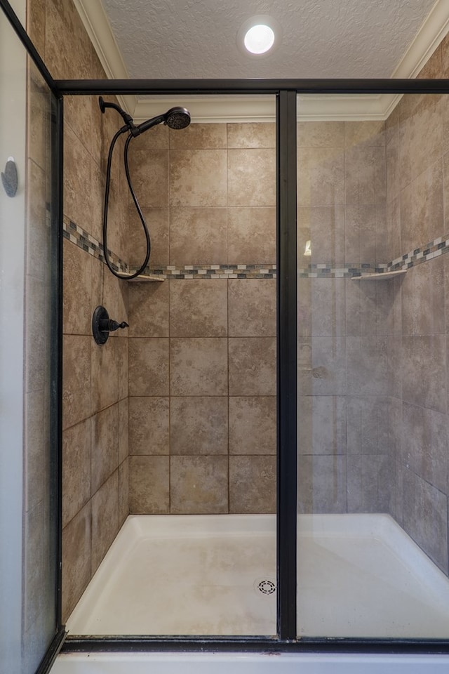 bathroom featuring an enclosed shower, ornamental molding, and a textured ceiling