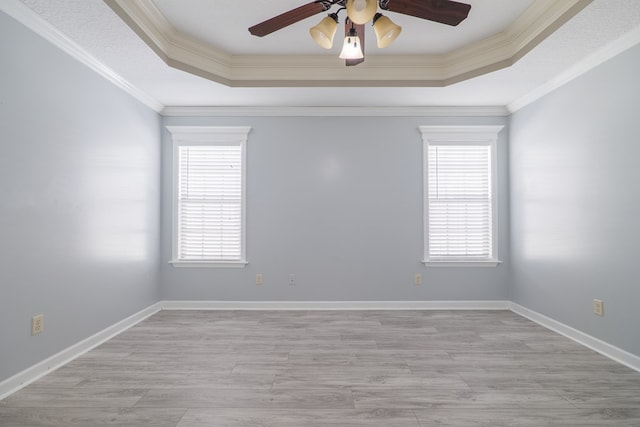 spare room featuring crown molding, ceiling fan, a tray ceiling, and light hardwood / wood-style flooring