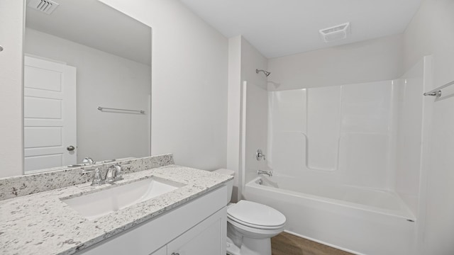 bathroom with visible vents, toilet, wood finished floors,  shower combination, and vanity