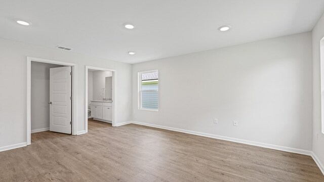 unfurnished bedroom with recessed lighting, visible vents, light wood-style flooring, ensuite bath, and baseboards