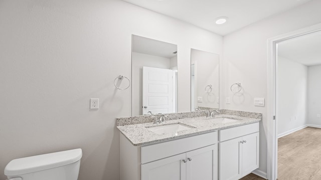 full bath featuring wood finished floors, a sink, toilet, and double vanity