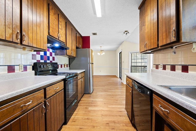 4312 Shiloh Trce, Valdosta, GA 31602 - kitchen featuring black appliances, under cabinet range hood, light wood-style flooring, backsplash, and a chandelier