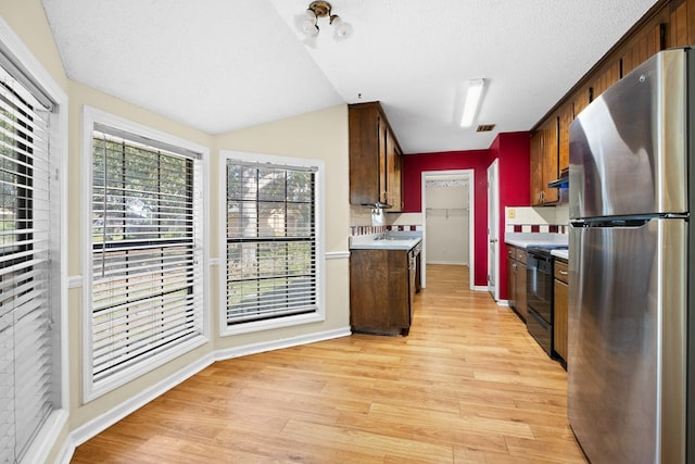 4312 Shiloh Trce, Valdosta, GA 31602 - kitchen with freestanding refrigerator, black range with electric stovetop, light wood finished floors, light countertops, and baseboards