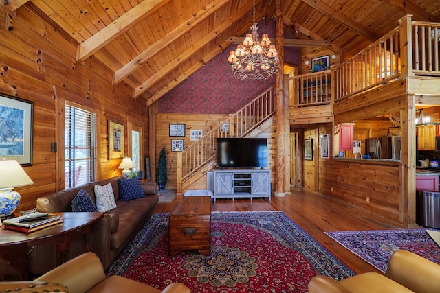 living room featuring hardwood / wood-style floors, high vaulted ceiling, wooden walls, beamed ceiling, and a chandelier