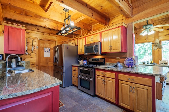 kitchen featuring ceiling fan, sink, stainless steel appliances, decorative light fixtures, and wooden walls