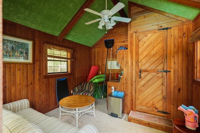 sitting room with carpet, lofted ceiling with beams, ceiling fan, and wooden walls